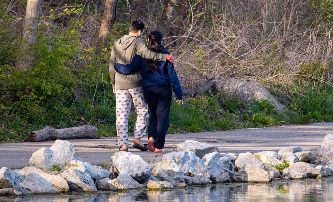 a man and woman hugging on a path near water