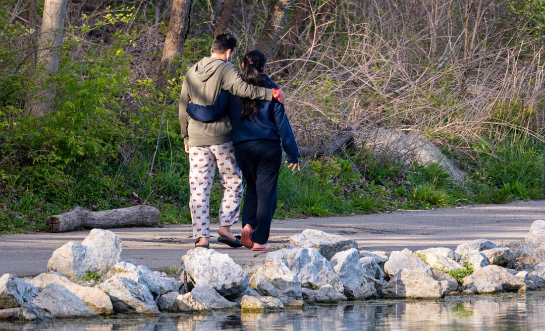 a man and woman hugging on a path near water