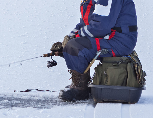 a person sitting on a snowy surface holding a fishing pole
