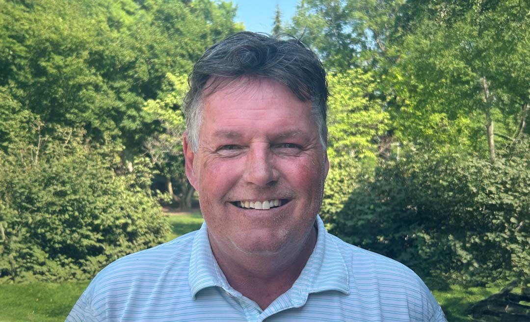 a man smiling in front of trees