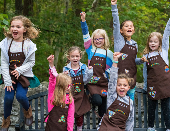 a group of girls wearing brown aprons and smiling