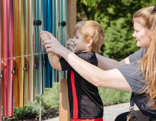 a woman and child playing with wind chimes