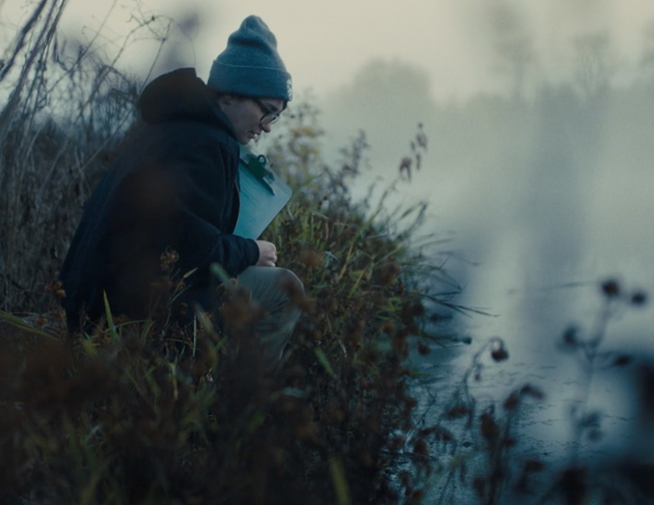 a person sitting on a grass next to a body of water