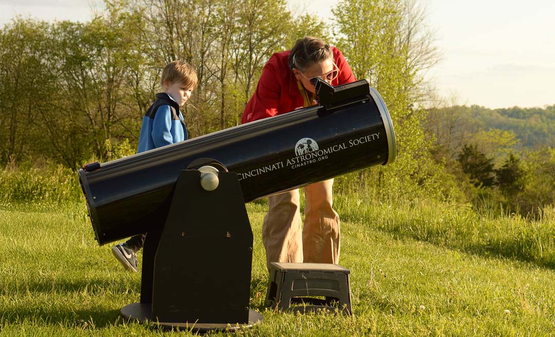 a woman and boy looking through a telescope