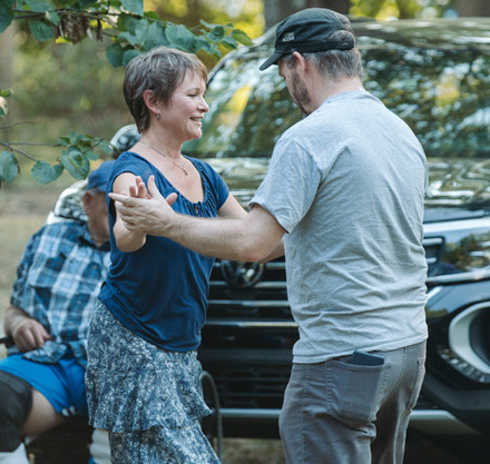 a man and woman dancing in front of a car