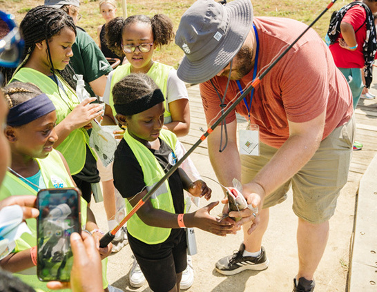 a man holding a fish with a group of people around it