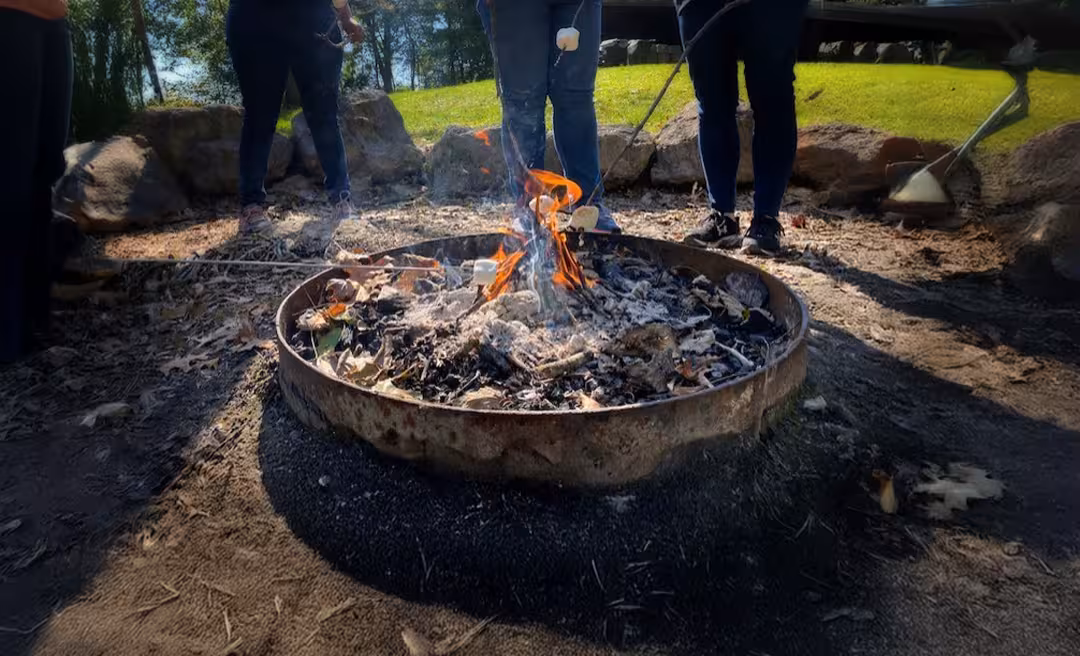 people standing around a fire pit with marshmallows