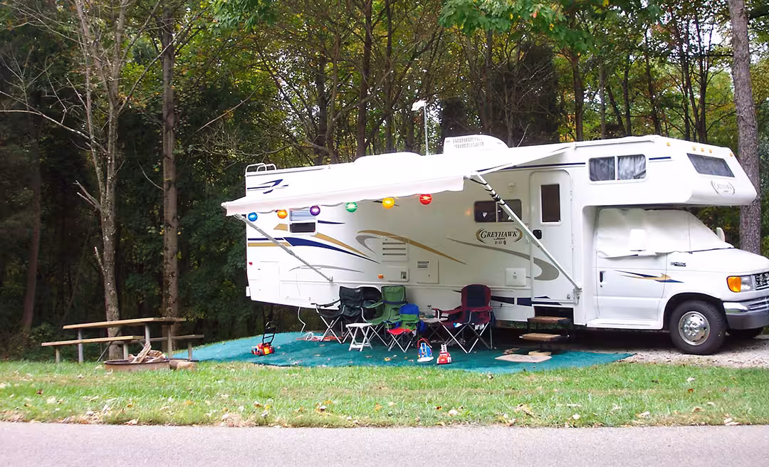 a white rv with chairs and a table in front of it