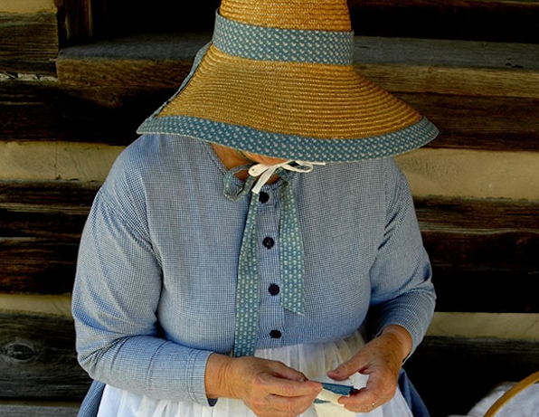 Woman in period costume working on a quilt