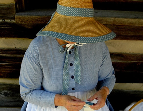 Woman in period costume working on a quilt