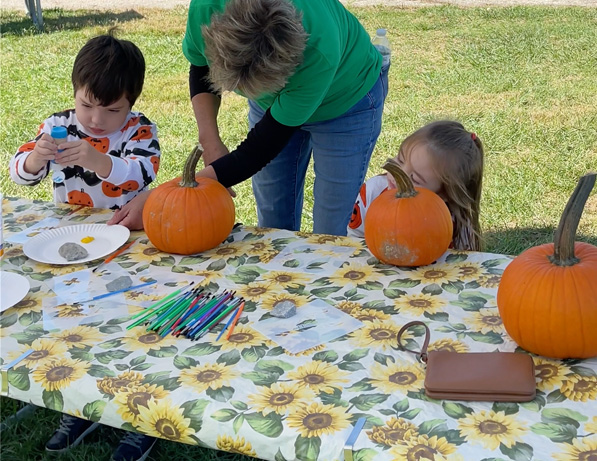 a woman and kids carving pumpkins