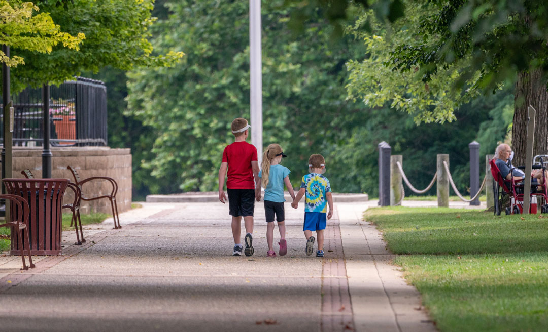 a group of kids walking on a sidewalk