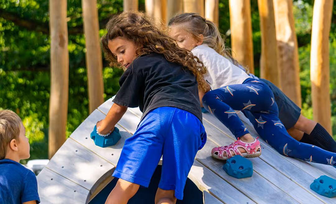 two girls climbing on a wooden structure