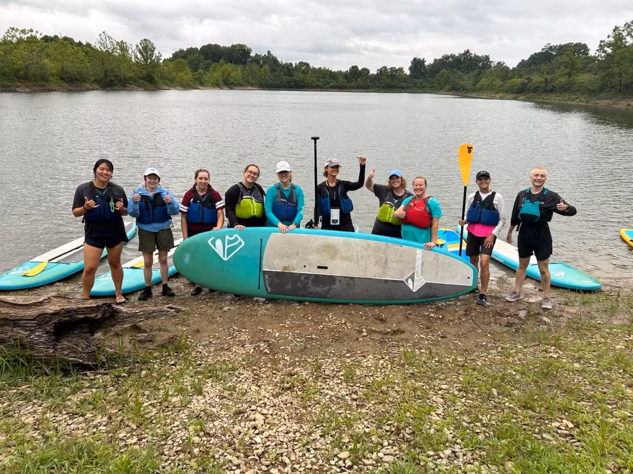 a group of people posing for a photo with paddle boards
