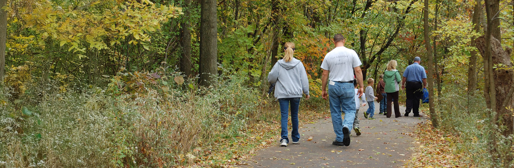 a man and woman walking on a path in the woods