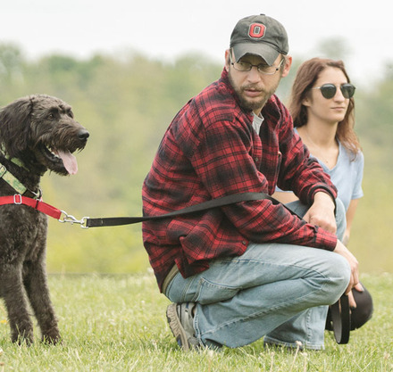 a man kneeling down with a dog on leash